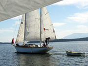 Couple and dog on sailboat, pulling a  dinghy