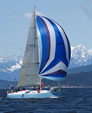 Sailboat in full sail in front of snow covered mountains